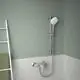 Chromfarbige Brausearmatur von Ideal Standard, montiert an der Wand, mit einem Halter für die Dusche und einem flexiblen Schlauch, vor einer hellen gefliesten Fläche.